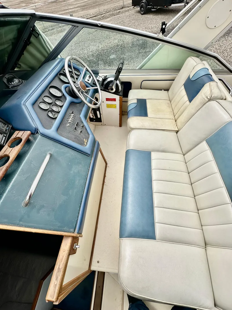 Slide: The Image of 1987 Sea Ray 270 Sundancer interior with blue and white seating and control panel. - 12
