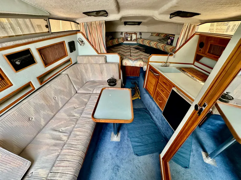 Slide: The Image of Interior of a 1987 Sea Ray 270 Sundancer boat with seating, table, and kitchenette. - 14