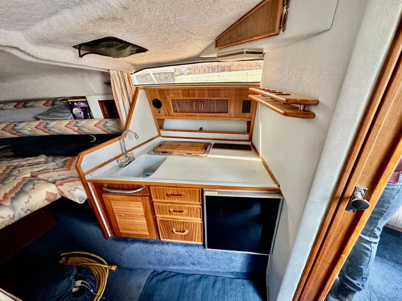Slide: The Image of 1987 Sea Ray 270 Sundancer cabin interior with kitchenette and cozy sleeping area. - 16