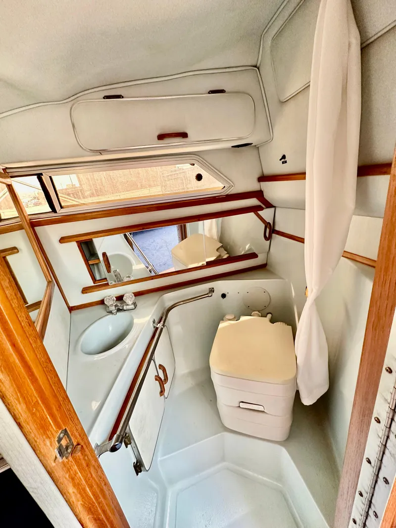 Slide: The Image of 1987 Sea Ray 270 Sundancer bathroom with sink, mirror, and compact toilet. - 19