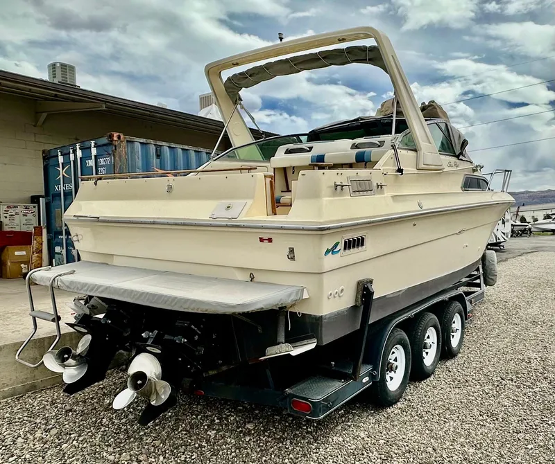 Slide: The Image of 1987 Sea Ray 270 Sundancer boat on trailer, parked outdoors, with cloudy sky background. - 3
