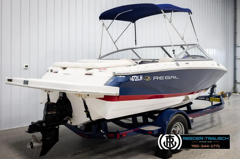 Slide: The Image of 2008 Regal 1900 boat on trailer, blue and white, with canopy, in indoor storage. - 6