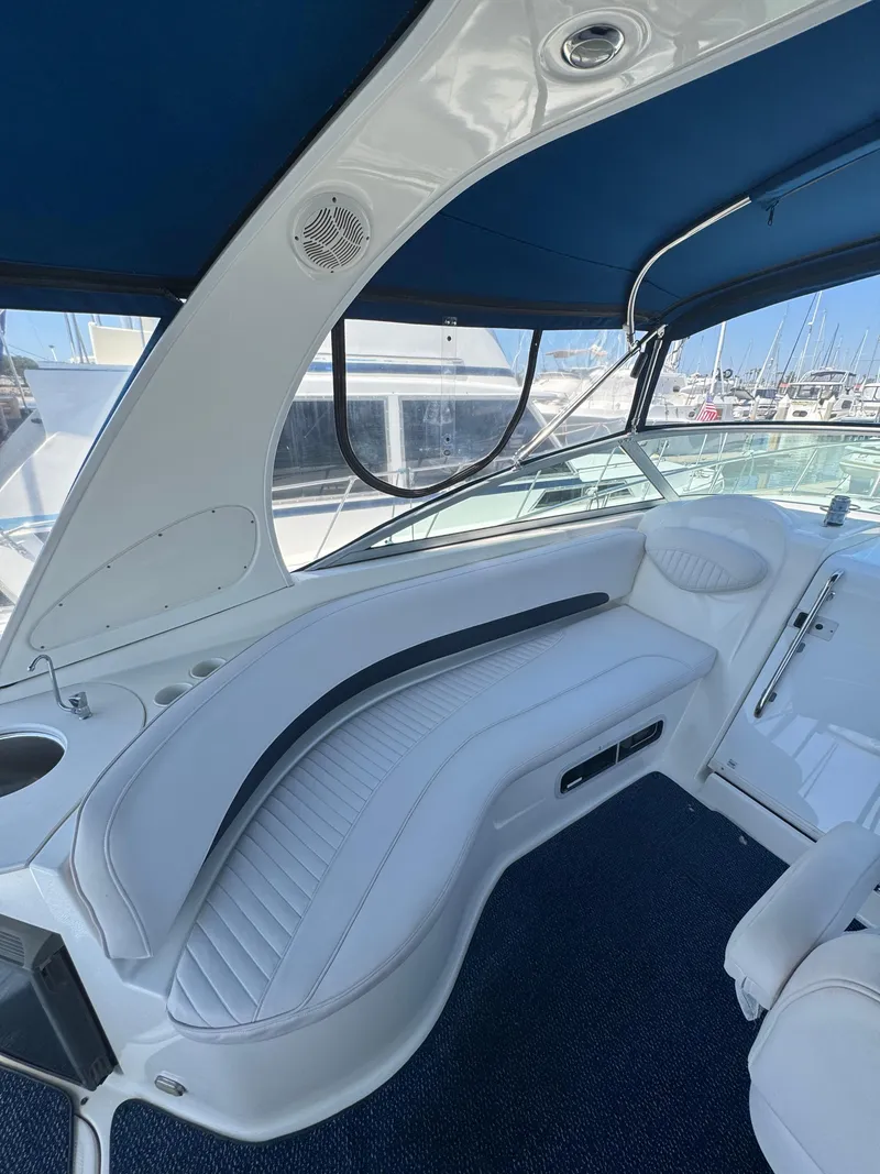 Slide: The Image of 2006 Bayliner 325 interior with white seating and blue canopy in a marina setting. - 11