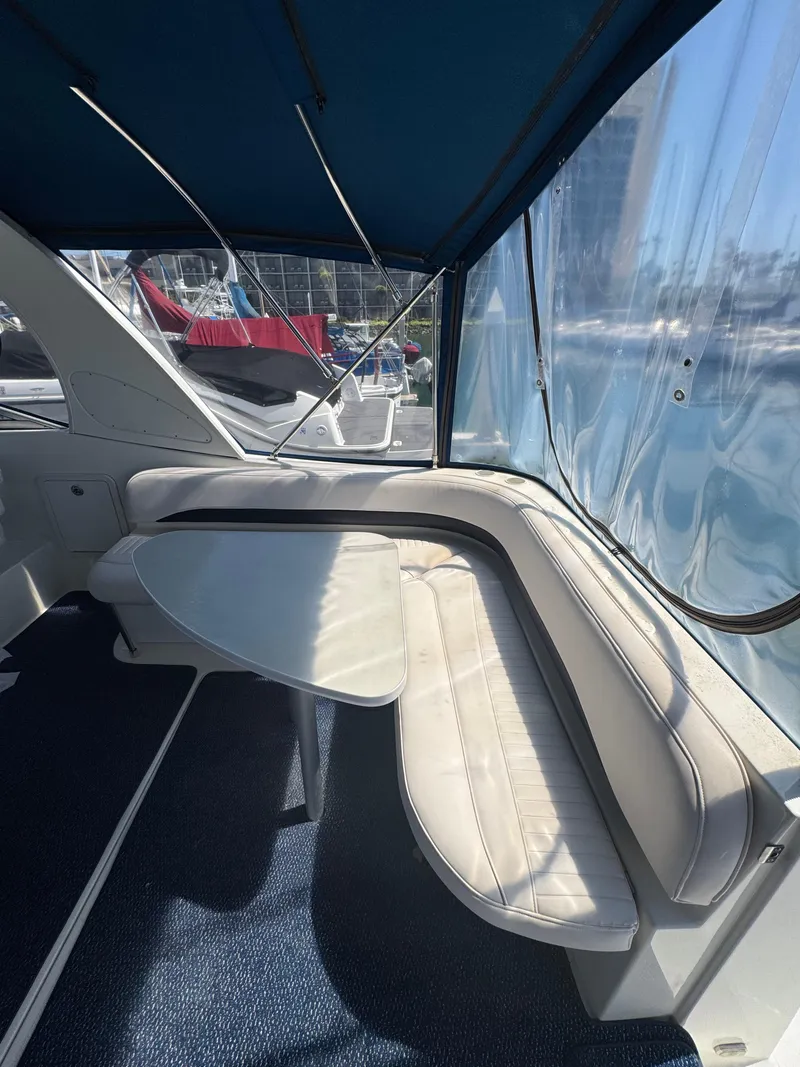 Slide: The Image of 2006 Bayliner 325 interior with cushioned seating and table under a blue canopy. - 12