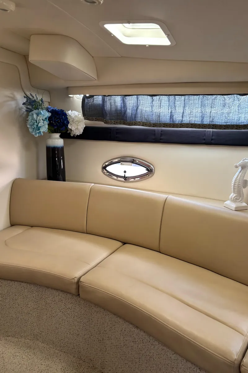 Slide: The Image of 2006 Bayliner 325 interior with beige seating, floral decor, and a small window. - 17