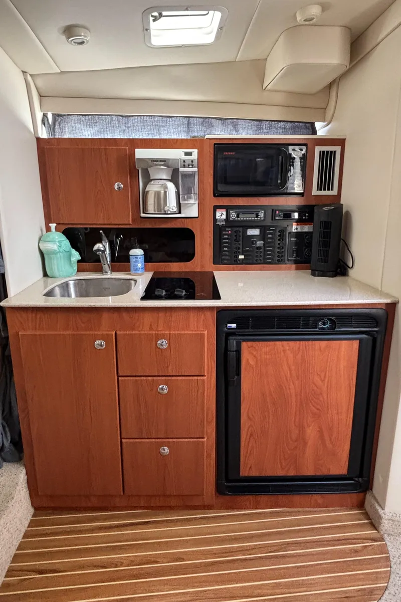 Slide: The Image of 2006 Bayliner 325 yacht kitchenette with wood cabinets, sink, microwave, and mini-fridge. - 18