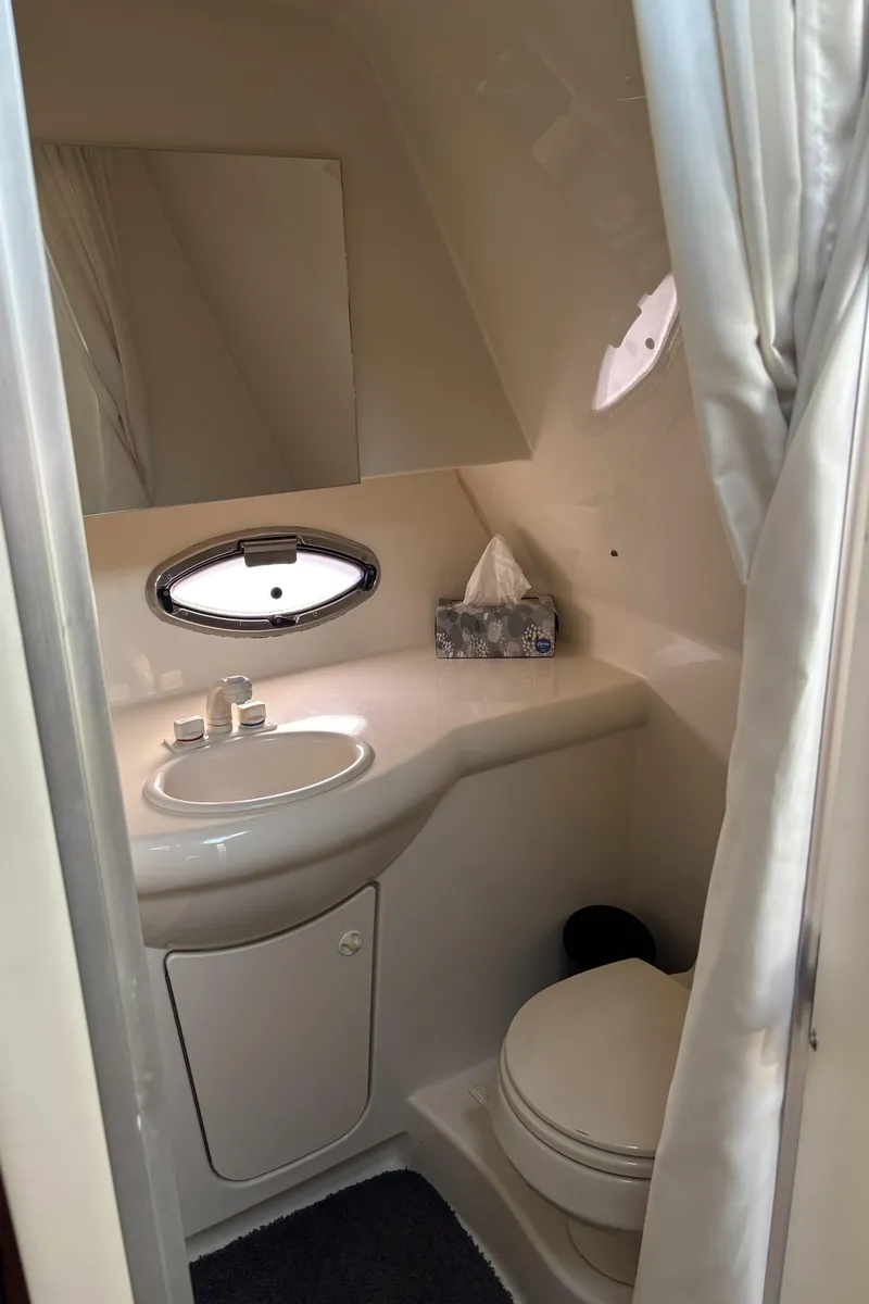Slide: The Image of 2006 Bayliner 325 boat bathroom with sink, toilet, and porthole window. - 21