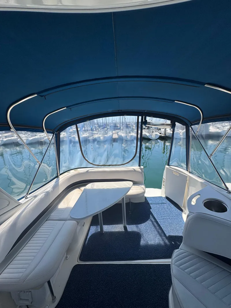 Slide: The Image of 2006 Bayliner 325 interior with blue canopy, white seating, and marina view. - 9