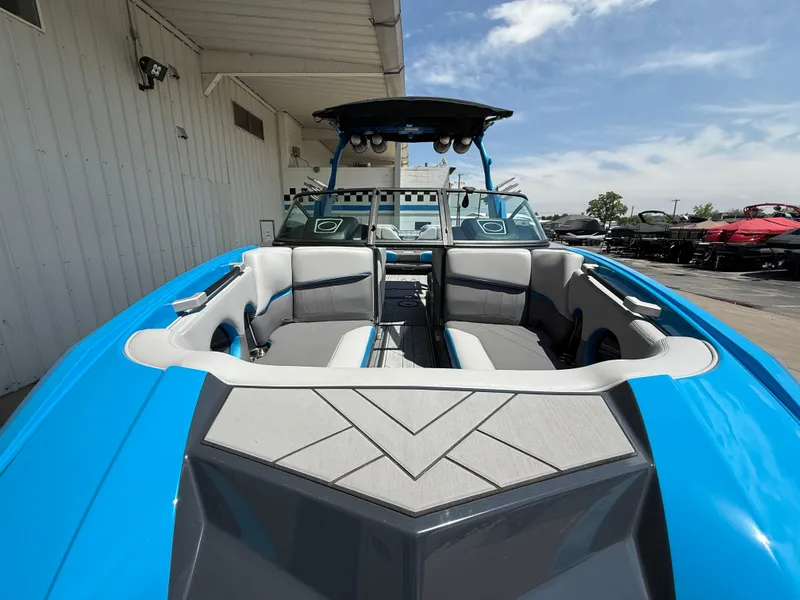 Slide: The Image of 2020 Supra SE550 boat with blue and gray interior, docked under a clear sky. - 2