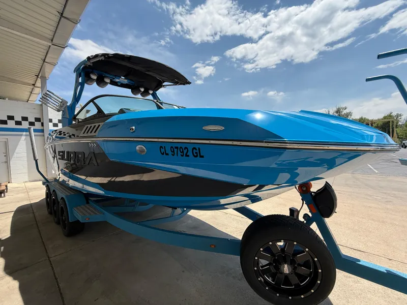 Slide: The Image of 2020 Supra SE550 boat in vibrant blue on a trailer under a clear sky. - 3