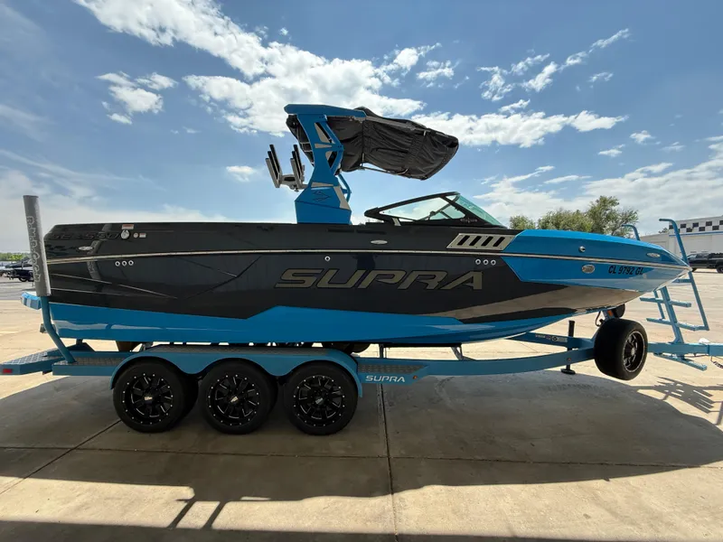 Slide: The Image of 2020 Supra SE550 boat on trailer, blue and black design, parked outdoors. - 4