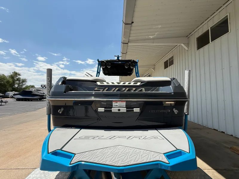 Slide: The Image of 2020 Supra SE550 boat rear view, parked outdoors under a clear sky. - 7