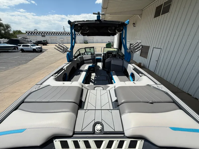 Slide: The Image of 2020 Supra SE550 boat interior with gray seating and blue accents, docked near a building. - 8