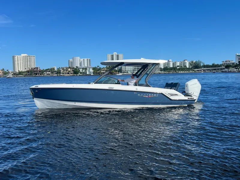 The Image of 2026 Monterey Elite 27 boat cruising on a sunny day with city skyline backdrop. - 0
