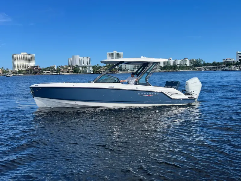 Slide: The Image of 2026 Monterey Elite 27 boat cruising on a sunny day with city skyline backdrop. - 9