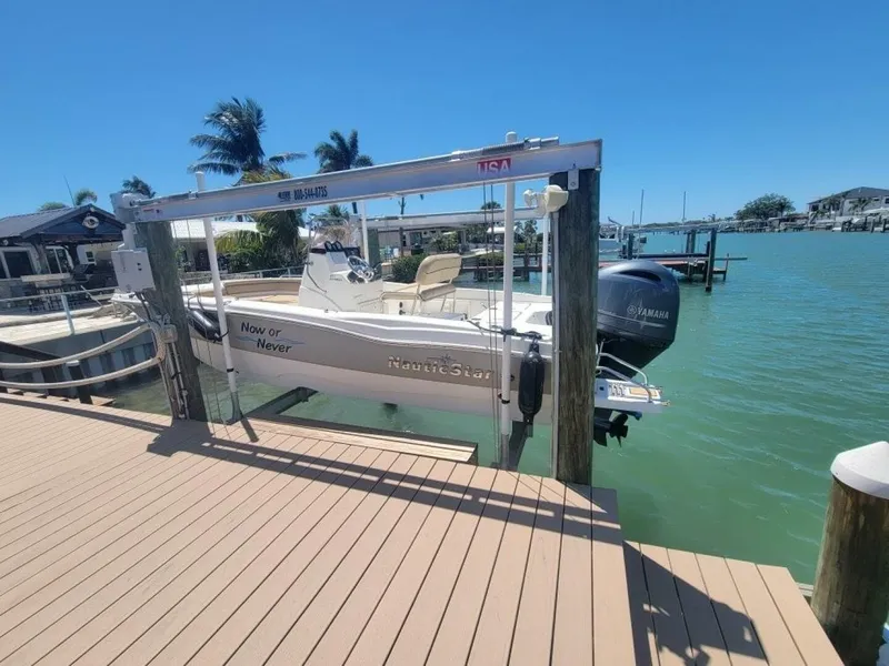 Slide: The Image of 2020 NauticStar 211 Hybrid boat docked on a sunny waterfront. - 0