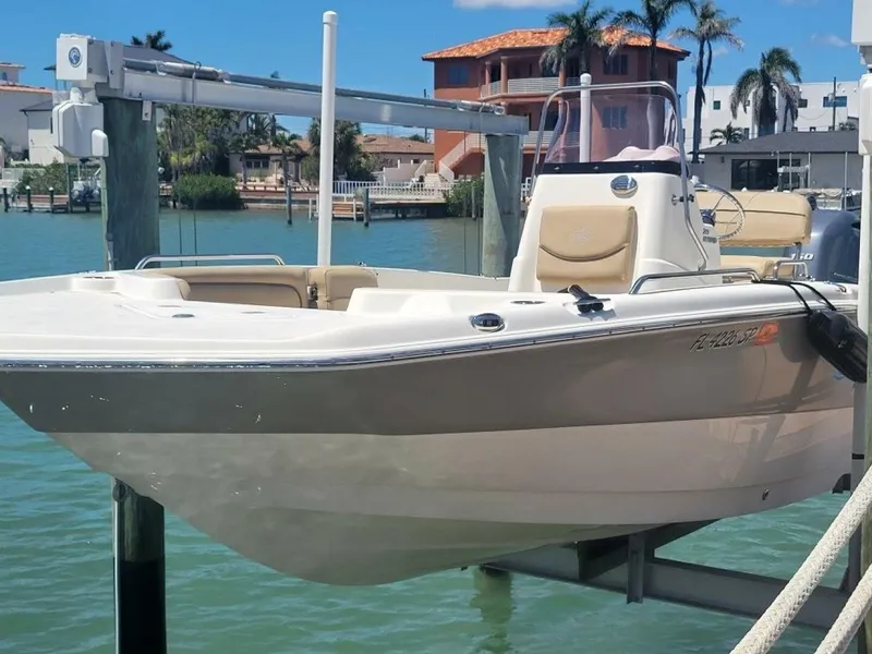 Slide: The Image of 2020 NauticStar 211 Hybrid boat docked with canopy, surrounded by palm trees. - 1