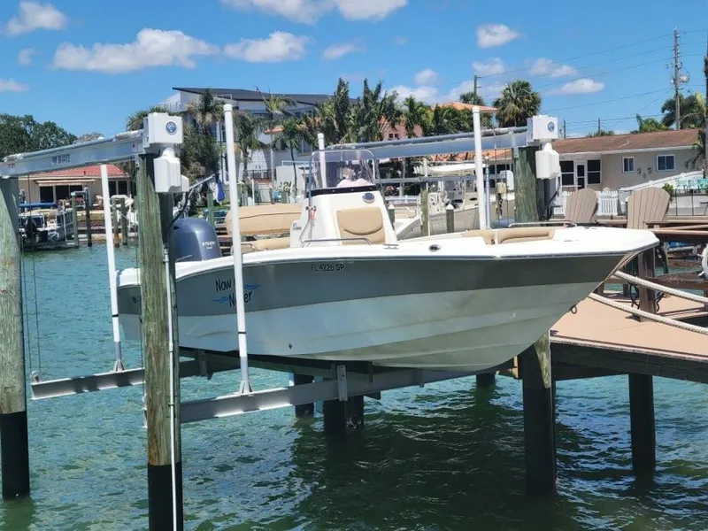 Slide: The Image of 2020 NauticStar 211 Hybrid boat docked on a sunny waterfront. - 2