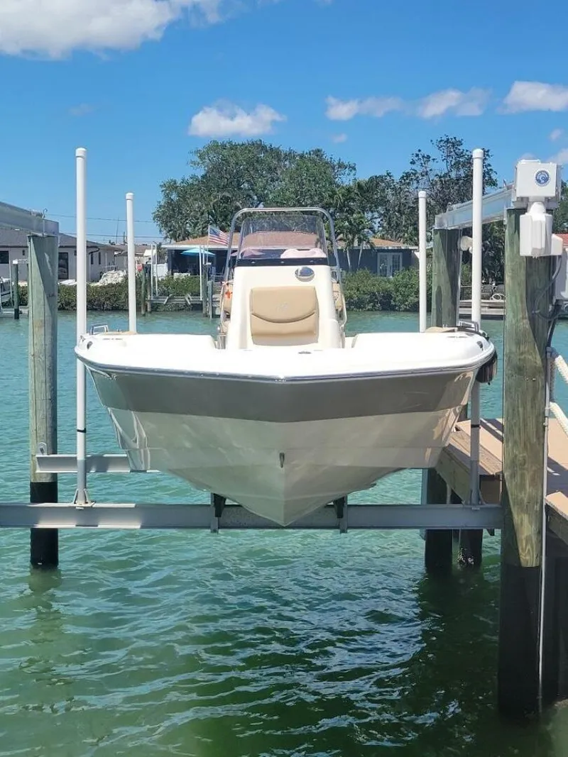 Slide: The Image of 2020 NauticStar 211 Hybrid boat on lift by dock, sunny day, palm trees. - 4