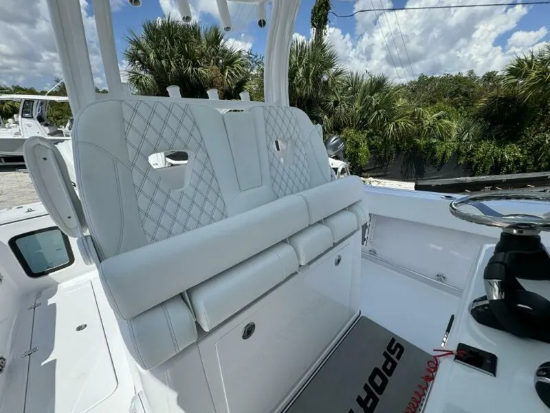 Slide: The Image of 2025 Sportsman 322 Open boat interior with white seating and steering wheel, surrounded by lush greenery. - 7