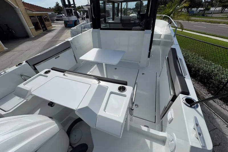 Slide: The Image of 2025 Jeanneau NC 795 SPORT S2 boat interior with seating and table, docked outdoors. - 2