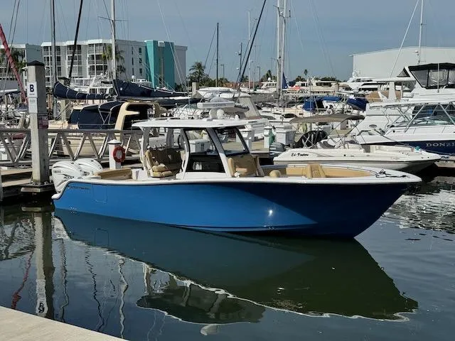 Slide: The Image of 2023 Sportsman 322 Open boat docked in a marina, surrounded by other vessels. - 0