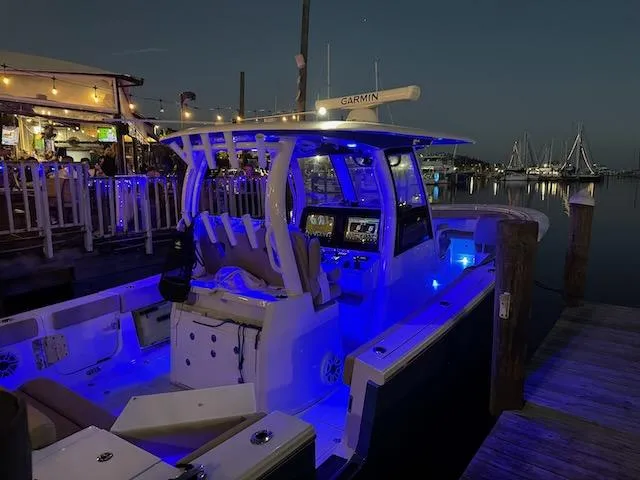 Slide: The Image of 2023 Sportsman 322 Open boat docked at night with blue LED lights. - 1