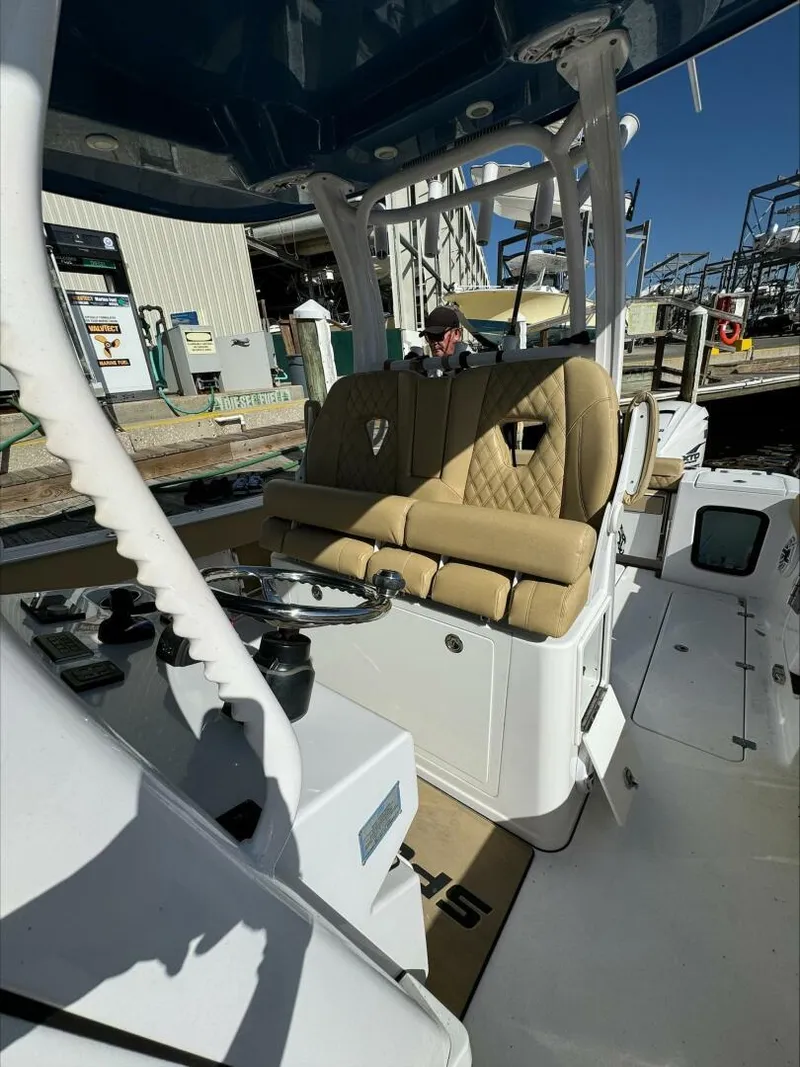 Slide: The Image of 2023 Sportsman boat interior with tan seats and steering wheel at a marina. - 10