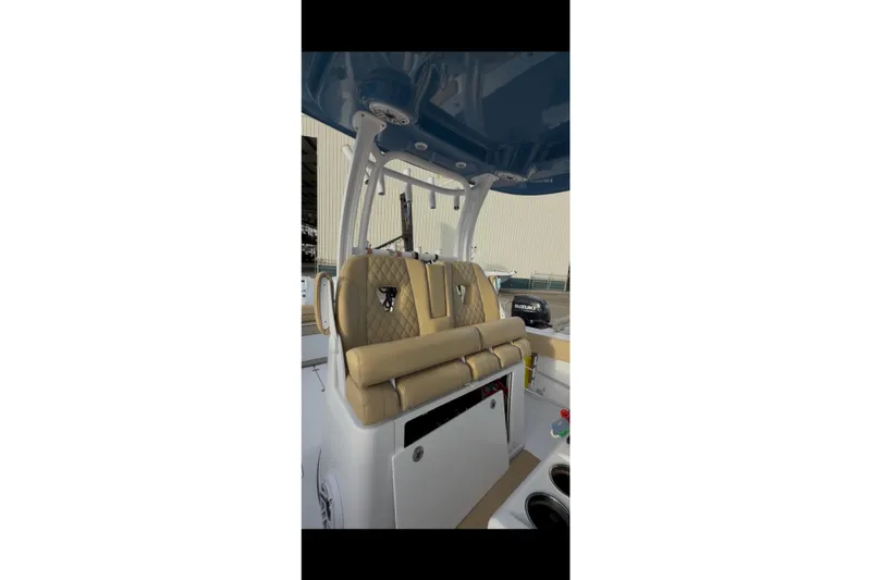 Slide: The Image of 2023 Sportsman Open 322 Center Console boat interior with tan seating and blue canopy. - 38
