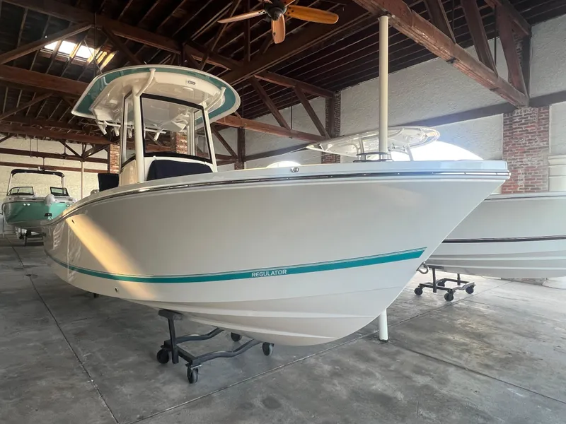 Slide: The Image of 2025 Regulator 24 XO boat in a wooden-roofed showroom, side view. - 2