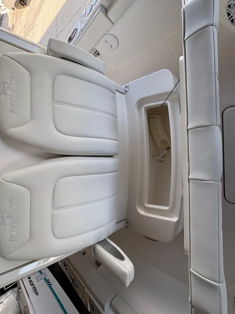 Slide: The Image of 2025 Regulator 26XO boat interior with white cushioned seating and storage compartment. - 17