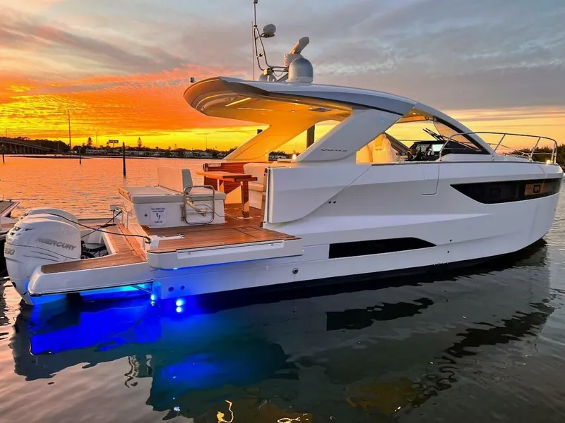 Slide: The Image of 2024 Jeanneau DB43 yacht at sunset, featuring sleek design and illuminated deck. - 1