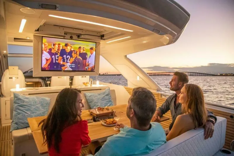 Slide: The Image of 2024 Jeanneau DB43 yacht with people watching TV at sunset on the water. - 6