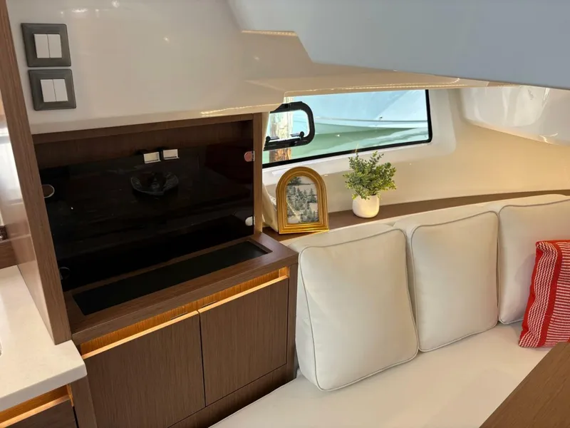 Slide: The Image of 2024 Jeanneau 12.5 Walk boat with spacious seating and modern design at a marina. - 17