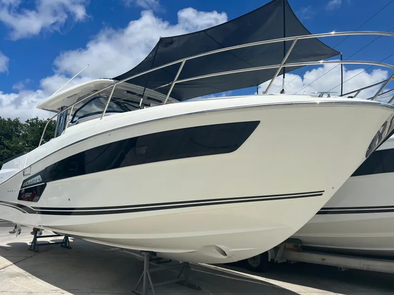 Slide: The Image of 2024 Jeanneau 12.5 Walk boat docked, featuring triple Yamaha engines, under clear blue sky. - 2