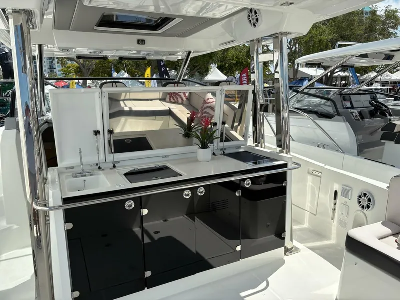 Slide: The Image of 2024 Jeanneau 12.5 Walk boat interior with seating and kitchenette at a marina. - 6