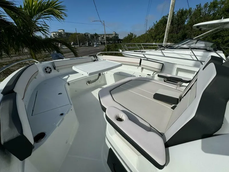 Slide: The Image of 2024 Jeanneau 10.5 CC boat interior with seating and table, surrounded by lush greenery. - 10