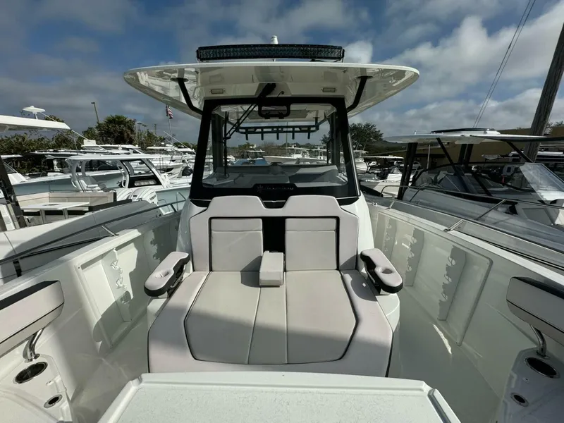 Slide: The Image of 2024 Jeanneau 10.5 CC boat interior with seating and helm, under a partly cloudy sky. - 11