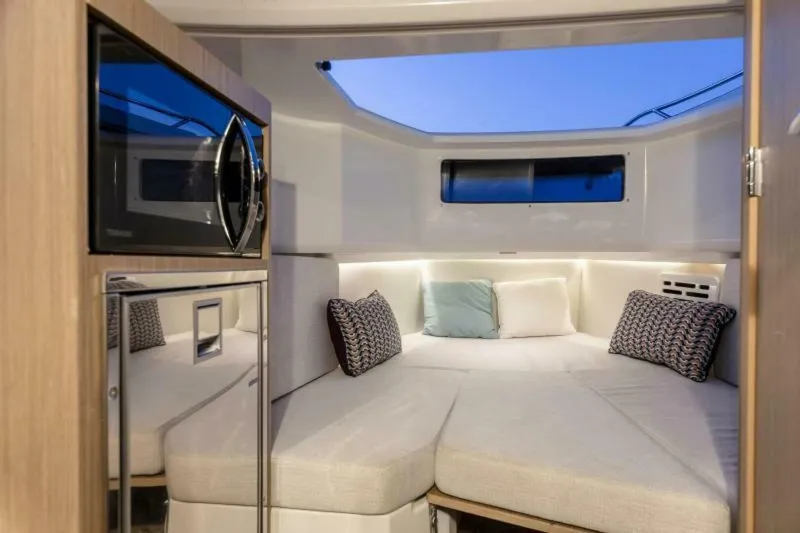 Slide: The Image of 2024 Jeanneau 10.5 CC cabin interior with cozy bed, pillows, and microwave. - 15