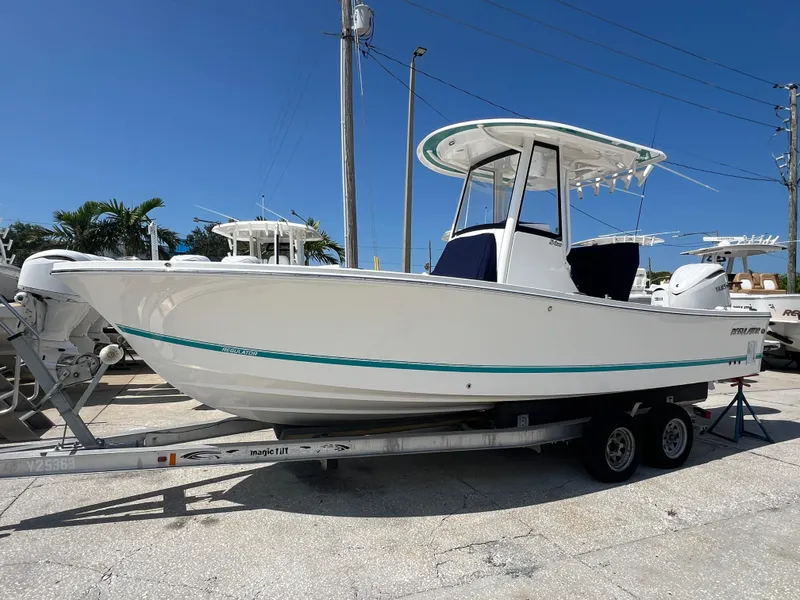 Slide: The Image of 2025 Regulator 24 XO boat on trailer, white hull, blue accents, sunny day. - 2