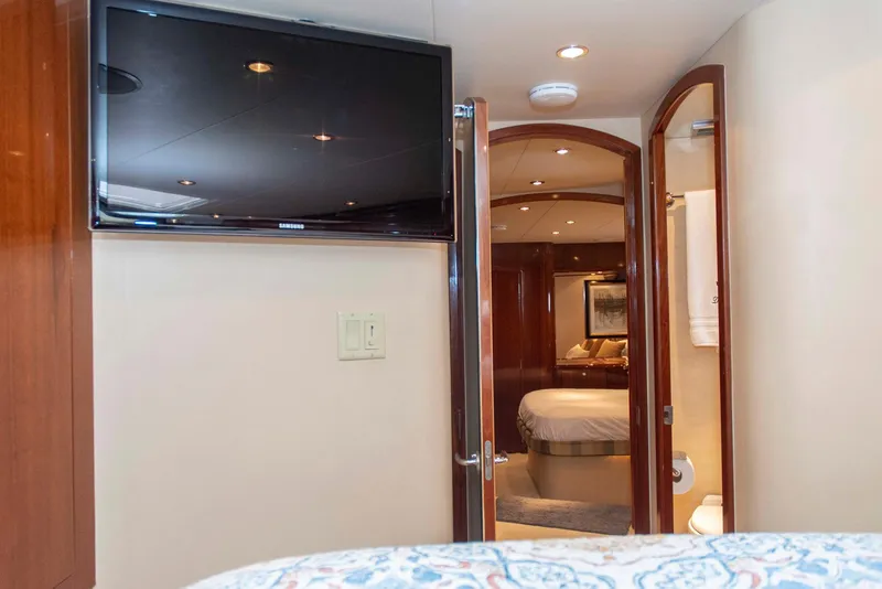 Slide: The Image of Interior of 2002 Hatteras 63 Yacht, featuring a bedroom, TV, and open bathroom door. - 49