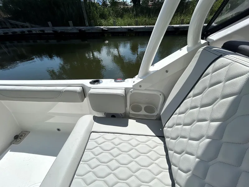 Slide: The Image of 2026 Pursuit DC 246 Dual Console boat interior with white quilted seating by the water. - 10