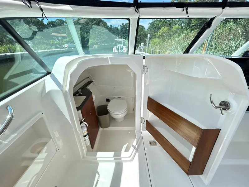 Slide: The Image of 2026 Pursuit DC 246 Dual Console boat interior with compact bathroom and sink. - 20