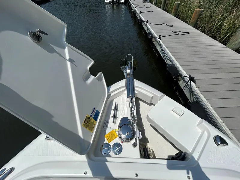 Slide: The Image of 2026 Pursuit DC 246 Dual Console boat at dock, open anchor compartment visible. - 24