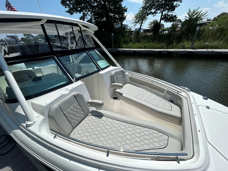 Slide: The Image of 2026 Pursuit DC 246 Dual Console boat with cushioned seating, docked by a serene waterway. - 25
