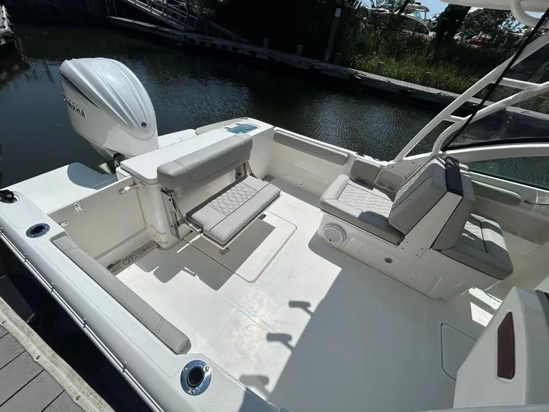 Slide: The Image of 2026 Pursuit DC 246 Dual Console boat interior with seating and Yamaha engine, docked by water. - 5