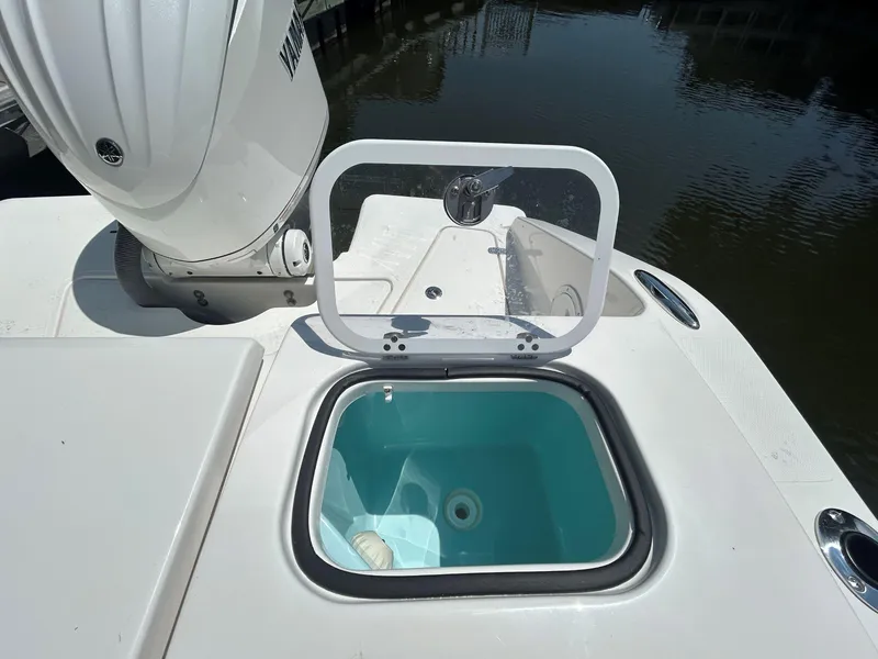 Slide: The Image of 2026 Pursuit DC 246 Dual Console boat with open storage compartment near water. - 7