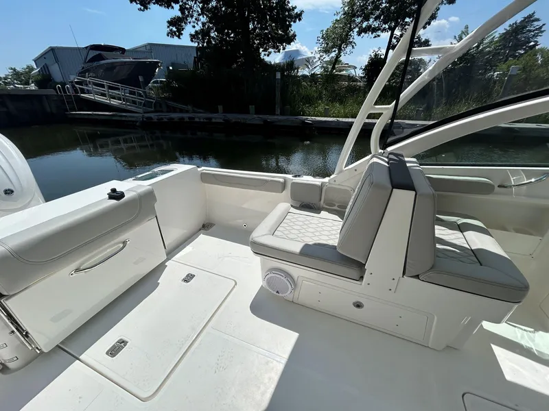 Slide: The Image of 2026 Pursuit DC 246 Dual Console boat interior with seating, docked by calm water. - 8
