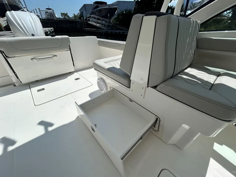 Slide: The Image of 2026 Pursuit DC 246 Dual Console boat interior with open storage drawer and cushioned seating. - 9