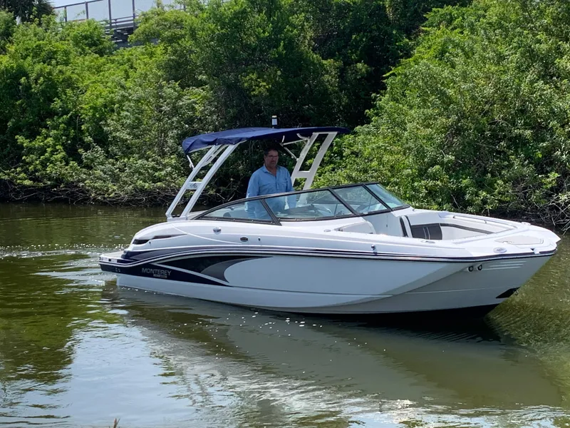 Slide: The Image of 2021 Monterey M6 boat cruising on a calm river with lush greenery. - 4